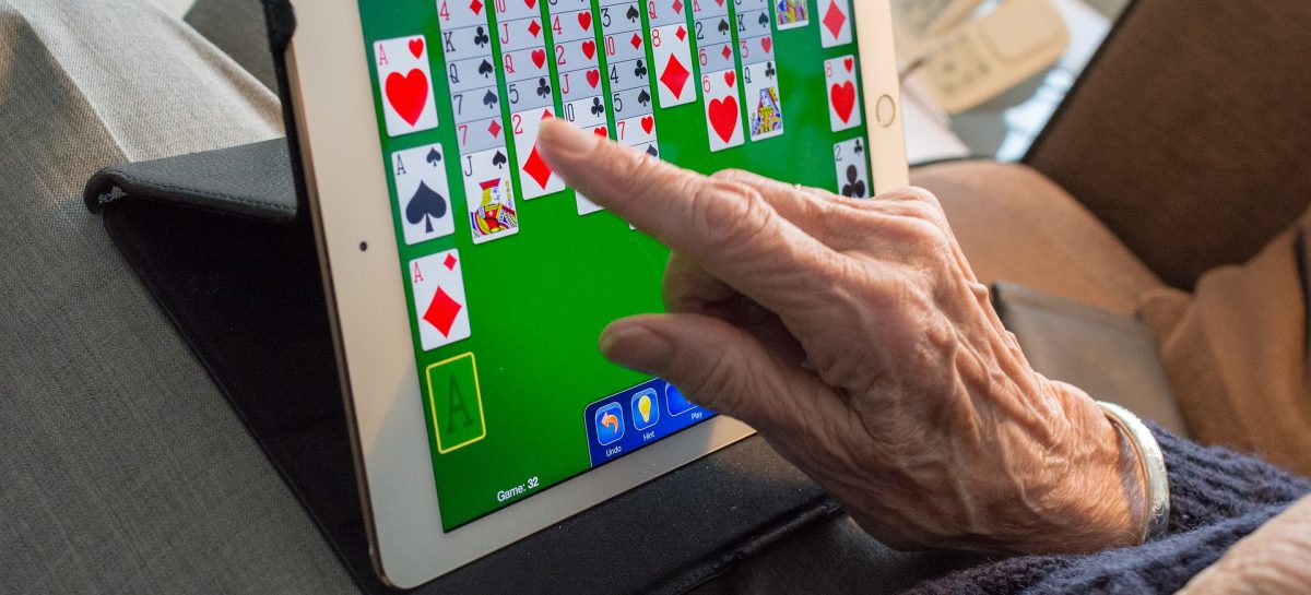 Seniorin spielt Solitär am Tablet-PC