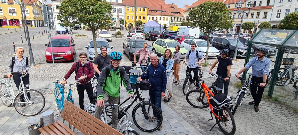 Die Teilnehmer der offiziellen Auftaktveranstaltung bei einer Fahrradtour lächeln in die Kamera.