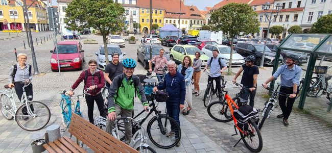 Die Teilnehmer der offiziellen Auftaktveranstaltung bei einer Fahrradtour lächeln in die Kamera.