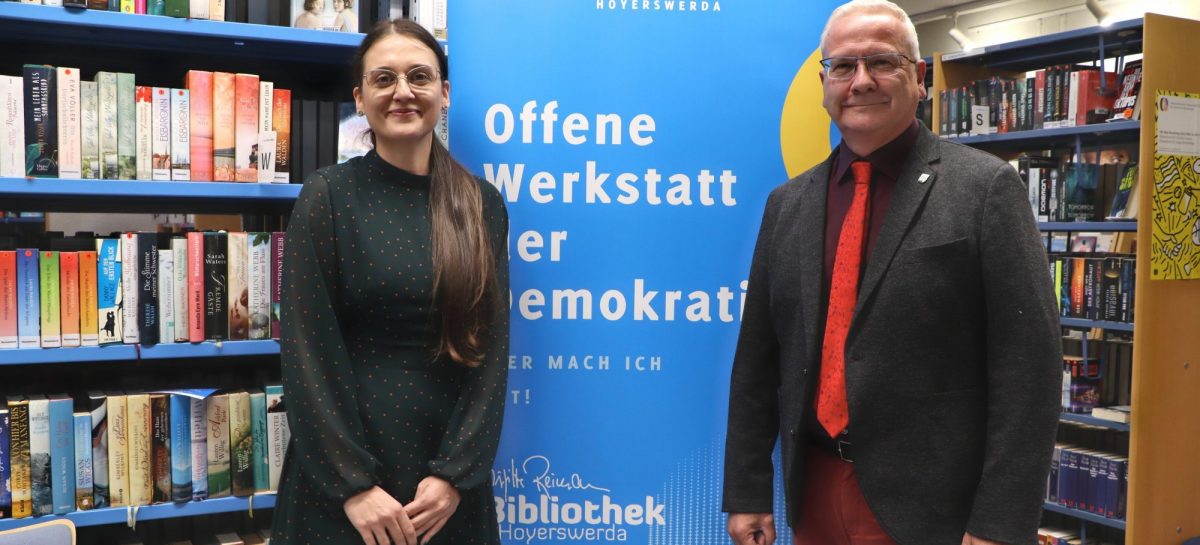 Biblioheksleiterin Maja Kos und Oberbürgermeister Torsten Ruban-Zeh vor einem Plakat der Offenen Werkstatt für Demokratie
