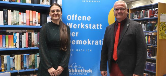 Biblioheksleiterin Maja Kos und Oberbürgermeister Torsten Ruban-Zeh vor einem Plakat der Offenen Werkstatt für Demokratie