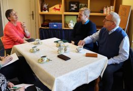 An einem Tisch in einer Buchhandlung sitzen mehrere Personen bei Kaffee. Links spricht Elisabeth Sygusch, Inhaberin des Buch und Musikhauses Sygusch. Ihr gegenüber sitzen Oberbürgermeister Torsten Ruban-Zeh und der Wirtschaftsförderer der Stadt Hoyerswerda, Sebastian Schindler, und hören zu.