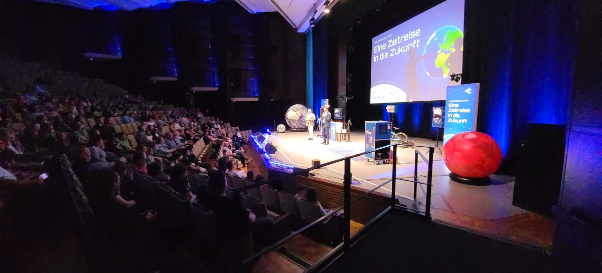 Während der DLR-Raumfahrt-Show sorgen Funkeneffekte und Bühnennebel für eine spektakuläre Atmosphäre. Das Publikum verfolgt die Vorführung aufmerksam aus dem Zuschauerraum der Lausitzhalle Hoyerswerda.