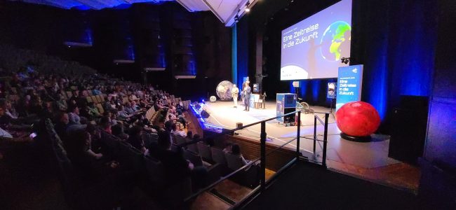 Während der DLR-Raumfahrt-Show sorgen Funkeneffekte und Bühnennebel für eine spektakuläre Atmosphäre. Das Publikum verfolgt die Vorführung aufmerksam aus dem Zuschauerraum der Lausitzhalle Hoyerswerda.