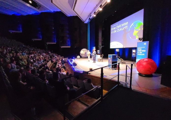 Während der DLR-Raumfahrt-Show sorgen Funkeneffekte und Bühnennebel für eine spektakuläre Atmosphäre. Das Publikum verfolgt die Vorführung aufmerksam aus dem Zuschauerraum der Lausitzhalle Hoyerswerda.
