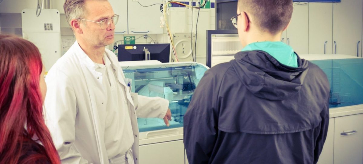 Ein Mitarbeiter des Lausitzer Seenland Klinikums erklärt zwei Jugendlichen in einem Laborbereich medizinische Geräte und Arbeitsabläufe während einer Praxistour im Rahmen des Zukunftsfeldes Gesundheit.
