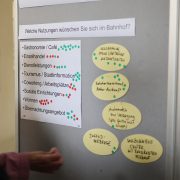 Moderationswand eines Beteiligungsworkshops zur Zukunft des Bahnhofs Hoyerswerda. Auf einer Übersicht zu möglichen Nutzungen wie Gastronomie, Dienstleistungen oder Tourismusinformation sind zahlreiche farbige Klebepunkte und handschriftliche Ideenvorschläge angebracht.