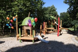 Übersichtsaufnahme des neuen Spielplatzes „Baumschätze“ mit zwei Spieltürmen, Rutschen und bunten Luftballons im Altstadtpark.