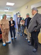 Sozialministerin Petra Köpping, Oberbürgermeister Torsten Ruban-Zeh, Dr. Matthias Jochmann und weitere Personen stehen mit Hauben und Überschuhen in einem Flur der Praxisklinik.