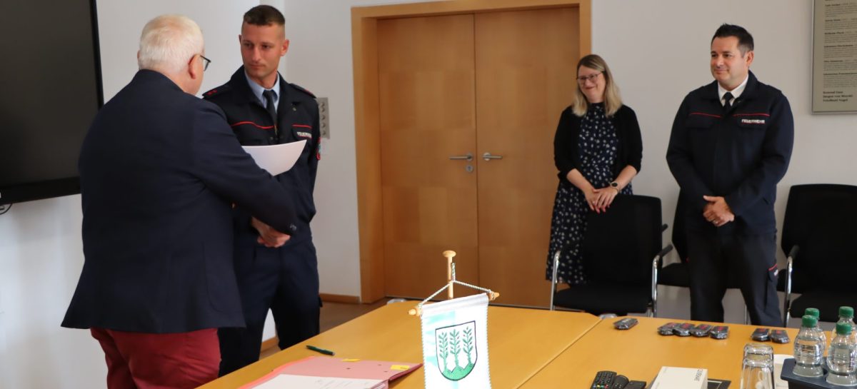 Oberbürgermeister Torsten Ruban-Zeh steht links einem uniformierten Feuerwehrbeamten gegenüber, der eine Urkunde hält. Rechts beobachten Frau Schröter und Feuerwehr-Fachbereichsleiter Benny Bastisch die Übergabe.