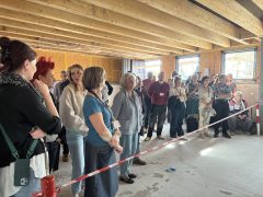 Zahlreiche Besucherinnen und Besucher stehen in einem Baustellenraum und verfolgen hinter einer Absperrung die Präsentation des WallBot.