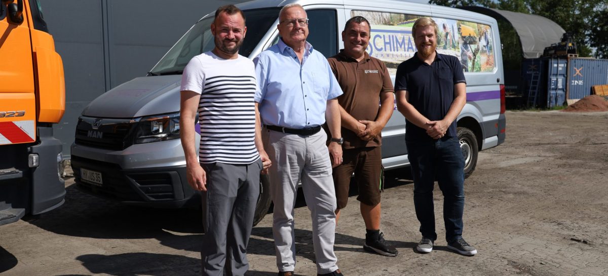 Vier Männer stehen auf dem Betriebsgelände vor einem beschrifteten Fahrzeug von Schimang Umweltservice. Zu sehen sind Geschäftsführer Tommy Schimang, Oberbürgermeister Torsten Ruban-Zeh, ein Mitarbeiter des Unternehmens und Wirtschaftsförderer Sebastian Schindler. Links ist ein Teil eines orangefarbenen Arbeitsfahrzeugs zu erkennen.