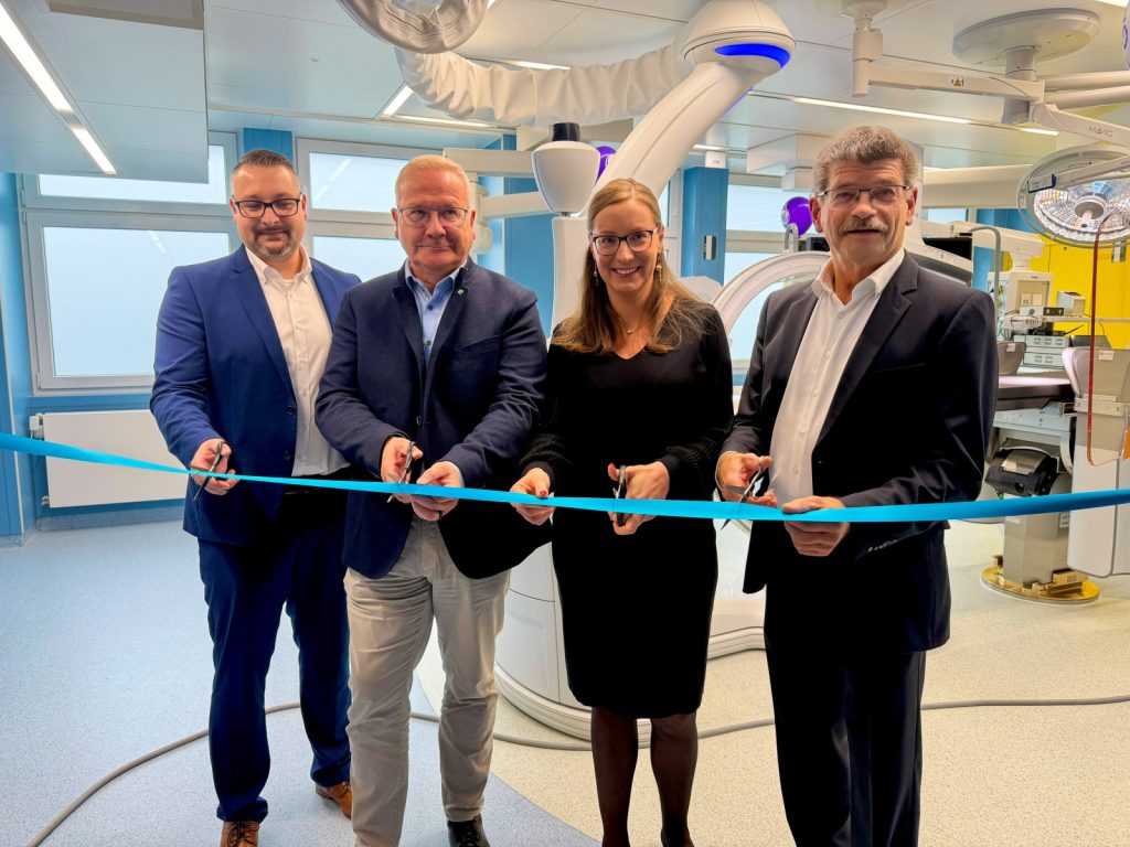 Vier Personen stehen im neuen Operationssaal des Lausitzer Seenland Klinikums und durchschneiden gemeinsam ein blaues Band. Im Hintergrund ist moderne Medizintechnik zu sehen.