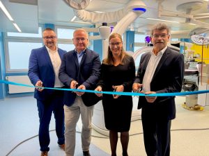 Vier Personen stehen im neuen Operationssaal des Lausitzer Seenland Klinikums und durchschneiden gemeinsam ein blaues Band. Im Hintergrund ist moderne Medizintechnik zu sehen.