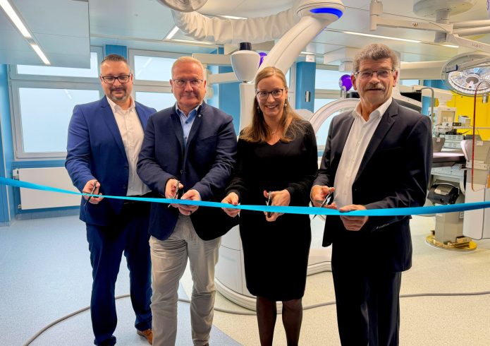 Vier Personen stehen im neuen Operationssaal des Lausitzer Seenland Klinikums und durchschneiden gemeinsam ein blaues Band. Im Hintergrund ist moderne Medizintechnik zu sehen.