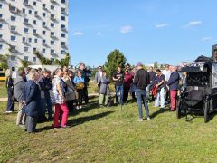Alternativtext: Eine Gruppe von Menschen steht auf einer Wiese im Zentralpark und hört einem Mann zu, der mit dem Rücken zur Kamera steht. Rechts sind der Oberbürgermeister und ein Lastenrad mit Veranstaltungstechnik zu sehen.