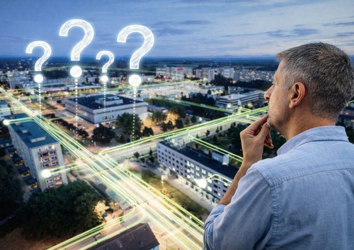 Mann blickt auf eine vernetzte Stadtlandschaft mit mehreren Fragezeichen als Symbol für offene Fragen zum Strukturwandel.