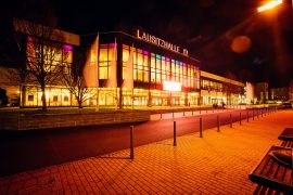 Nächtliche Außenansicht der Lausitzhalle mit beleuchteter Glasfassade und Schriftzug „Lausitzhalle