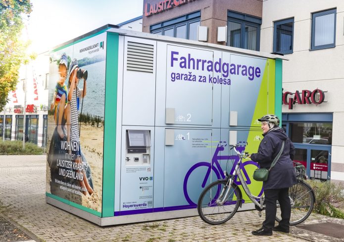 Person mit einem Fahrrad vor einer Fahrradgarage.